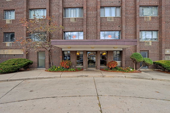 Front view of a multi-story brick building entrance with a canopy.