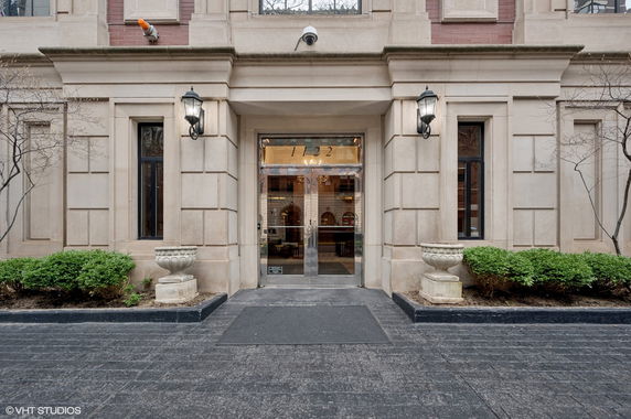 Front view of a building entrance with decorative lampposts and plants.