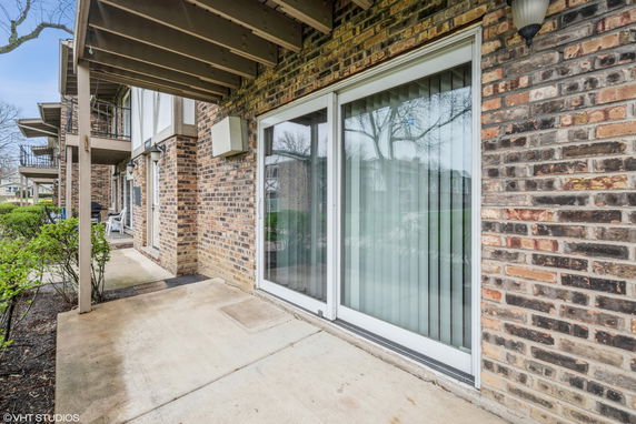 Exterior view of a multi-story building with brick walls and sliding glass doors.