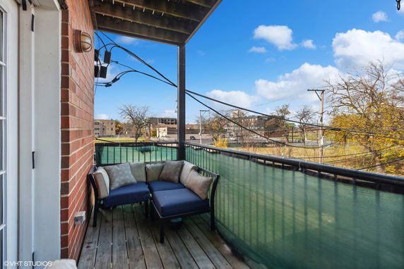 View from a balcony with seating overlooking surrounding buildings and power lines.