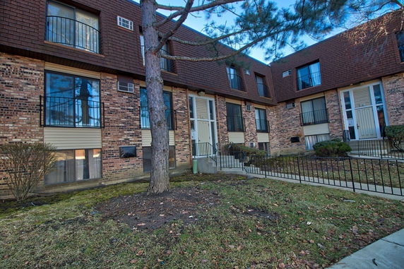 Front view of a multi-story brick building with balconies and a central entrance.