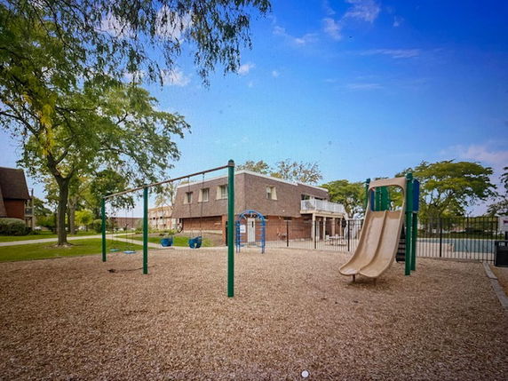 Playground with swings and slide in front of a two-story building.