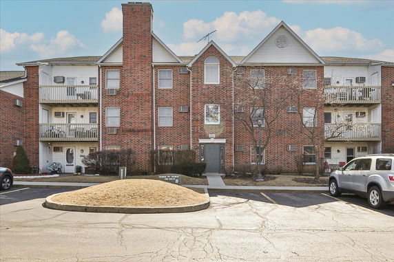 Front view of a multi-story brick apartment building with balconies.