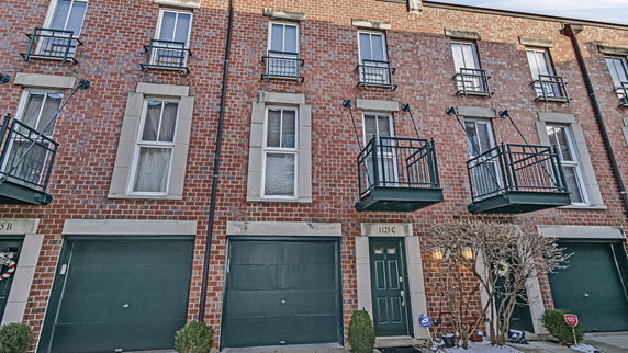 Front view of a multi-story brick townhouse with balconies and a garage.