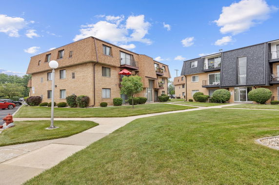Front view of a two-story apartment building with balconies and brick facade.
