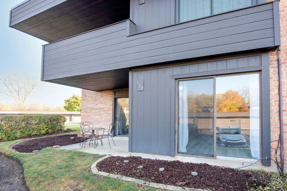 Front view of a contemporary building with a small patio and sliding glass door.