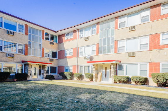 Front view of a multi-story apartment building with multiple entrances.