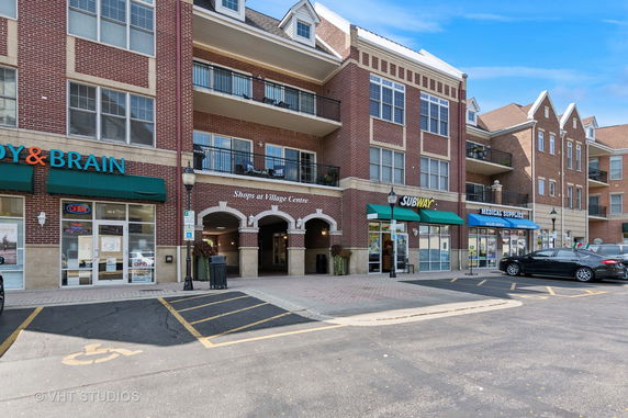 Front view of a multi-story building with shops on the ground floor.