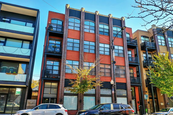Front view of a multi-story building with large windows and balconies.