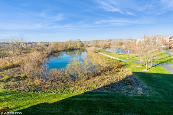 View of a grassy landscape with a pond and trees seen from a building.