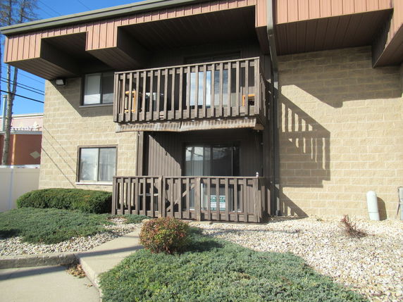 Front view of a two-story building with balconies and a stone exterior.
