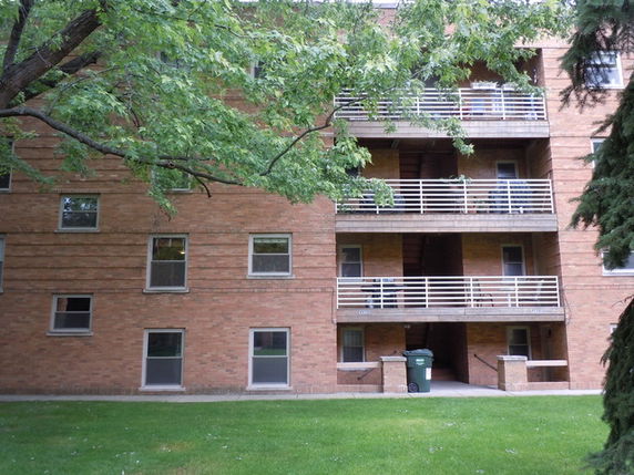 Front view of a multi-story brick apartment building with balconies.