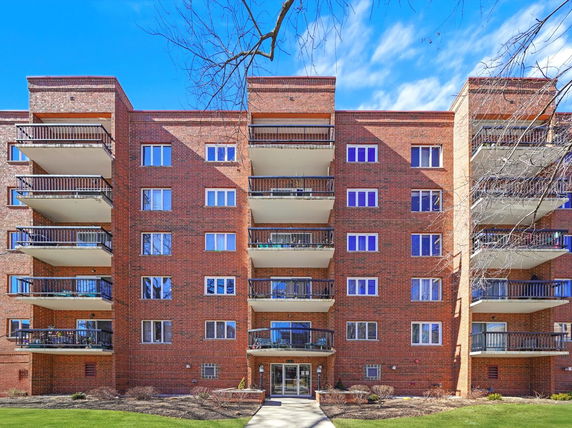 Front view of a multi-story brick apartment building with balconies.