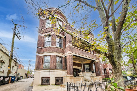 Front view of a multi-story brick building with bay windows and a covered entrance.