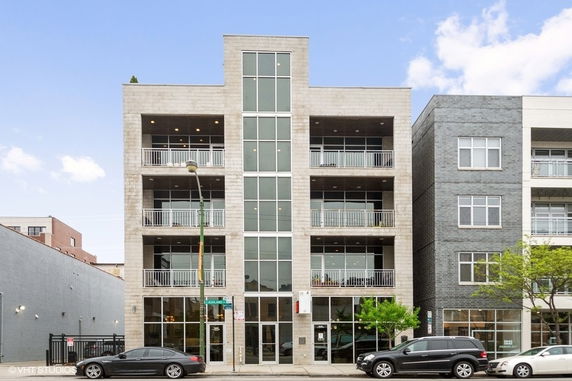 Front view of a multi-story building with balconies and large windows.
