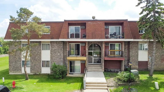 Front view of a multi-story residential building with balconies and a central entrance.