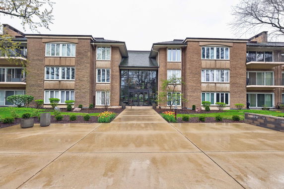 Front view of a multi-story building with a central glass entrance and brick facade.