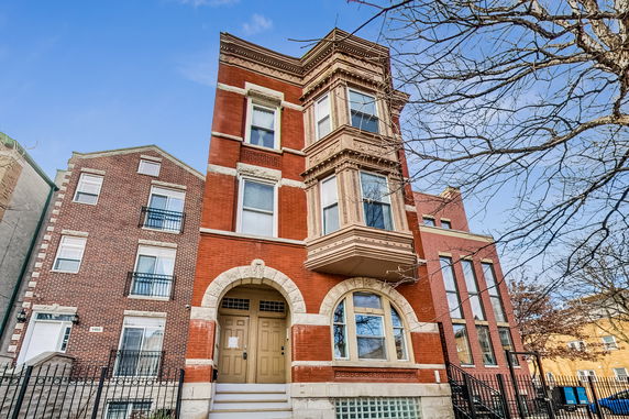Front view of a three-story red brick building with ornate architectural details.