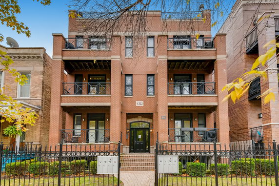 Front view of a multi-story brick residential building with balconies.
