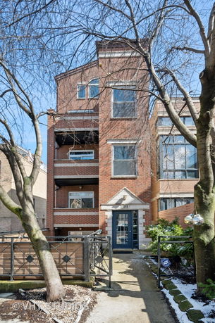 Front view of a multi-story brick house with balconies and front entrance.