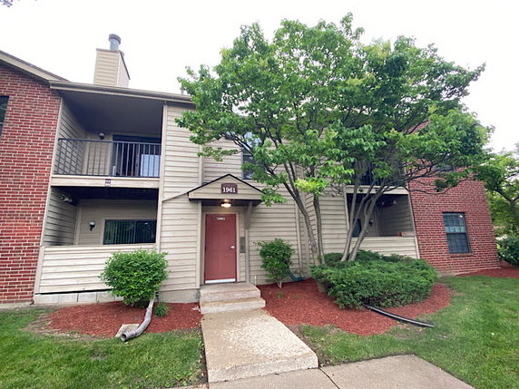 Front view of a two-story building with a red door and balconies.