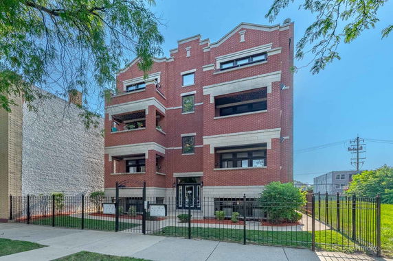 Front view of a brick multi-story residential building with balconies.