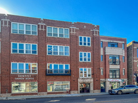 Front view of a multi-story brick building with shops on the ground floor.