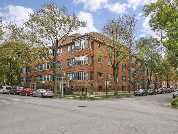 Front view of a multi-story brick apartment building on a street corner.