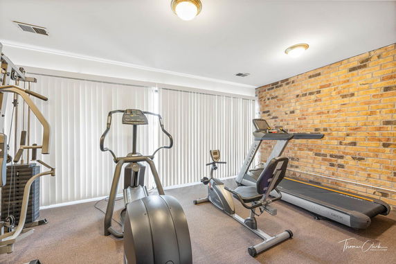 Indoor gym with exercise equipment including a treadmill, elliptical machine, and exercise bike.