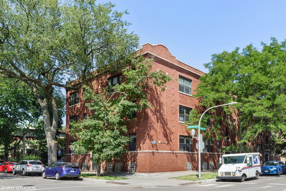Front view of a three-story red brick building on a street corner.