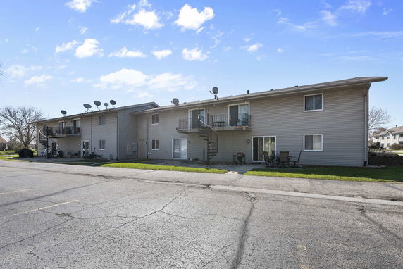 Front view of a two-story apartment building with satellite dishes and balconies.