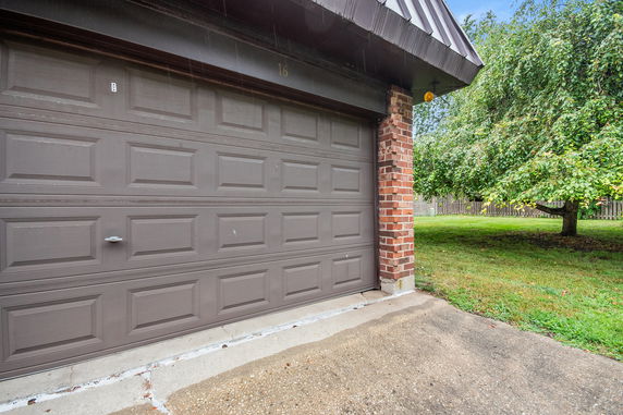 Partial view of a garage door with a brick column and metal roof trim.