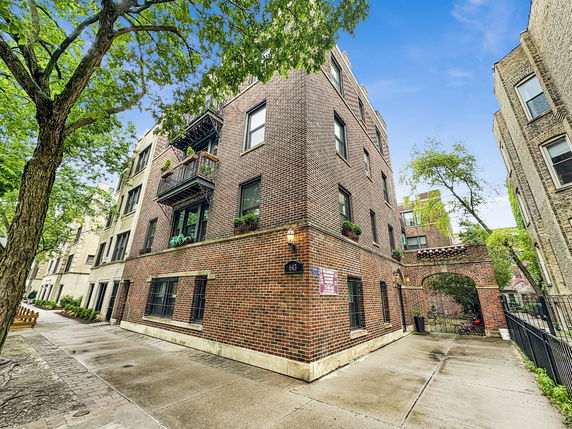 Front view of a multi-story brick apartment building with balconies.