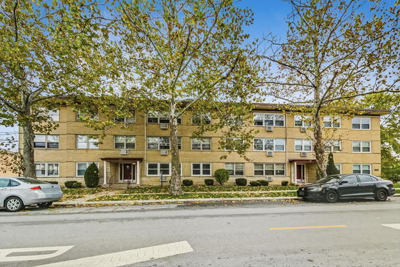 Front view of a three-story brick apartment building with multiple windows.