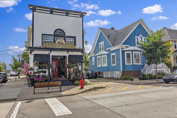 Front view of a flower shop with an upper residential unit next to a blue residential house.
