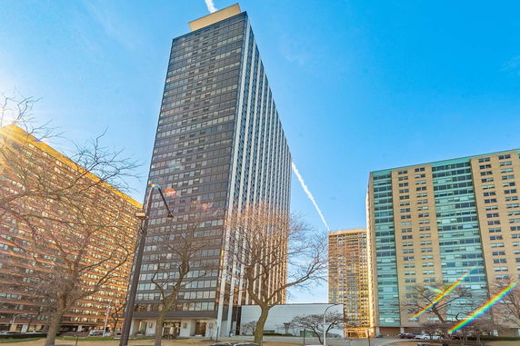 Front view of a tall residential building with multiple floors and large windows.