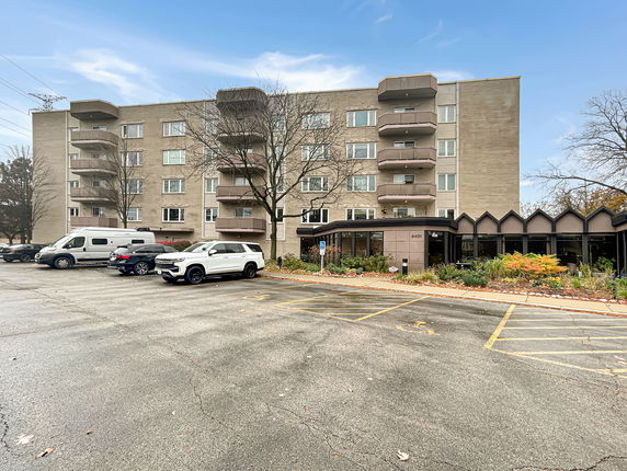 Front view of a multi-story building with parking area in front.