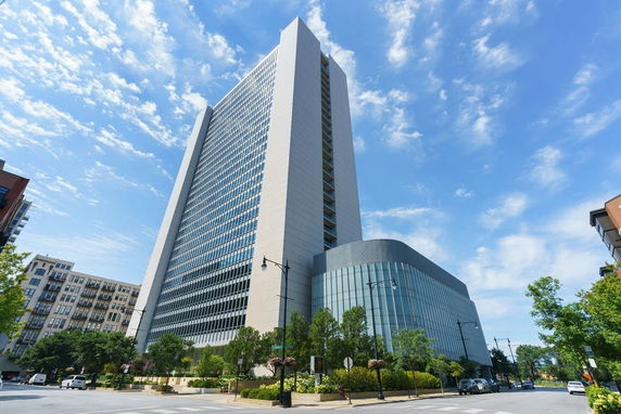 Front view of a tall, modern high-rise building against a blue sky.