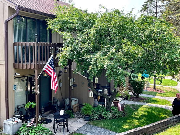 Front view of a two-story house with a balcony and an American flag.