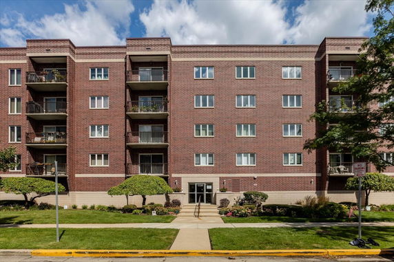 Front view of a multi-story brick apartment building with balconies.