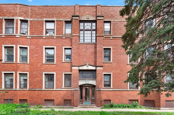 Front view of a brick apartment building with multiple windows.
