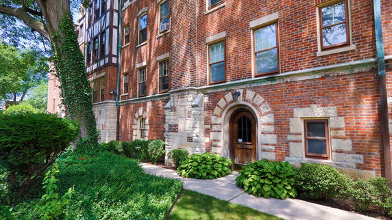 Front view of a multi-story brick building with arched doorway and windows.