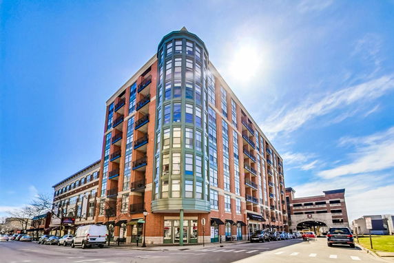 Front view of a multi-story brick building with glass windows and balconies.