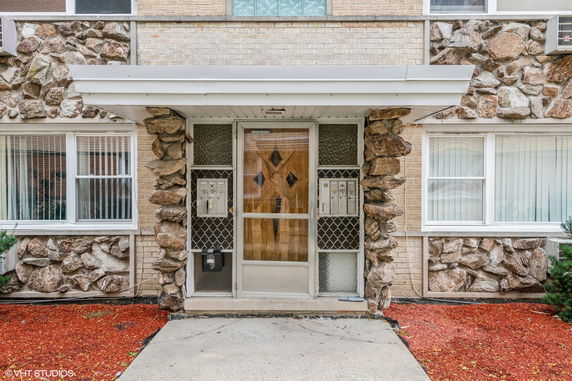 Front view of a building entryway with stone accents and a wooden door.