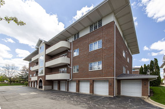 Front view of a multi-story brick building with balconies and multiple garages.