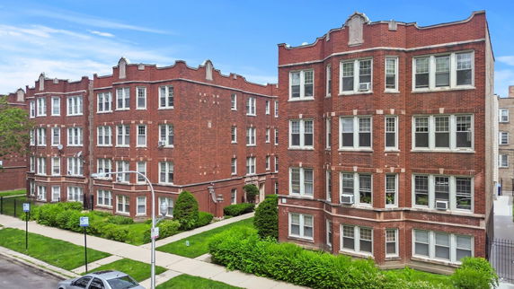 Front view of brick apartment buildings with multiple windows and decorative roofline.