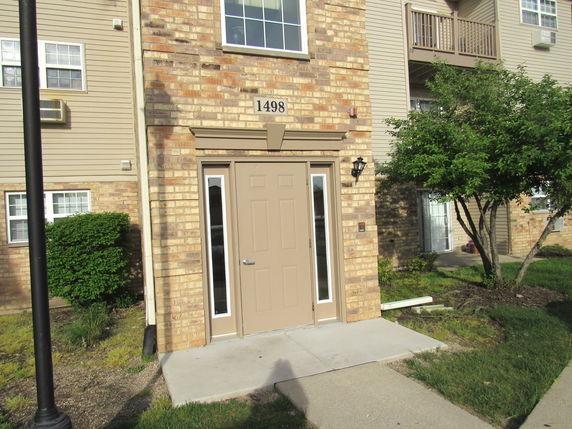 Front view of a multi-story brick apartment building entrance.