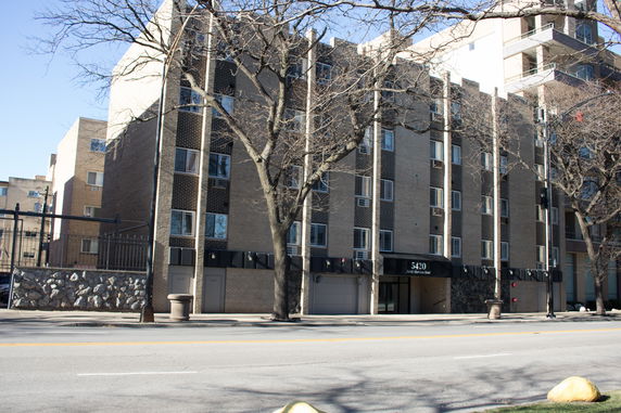 Front view of a multi-story brick building with large windows.