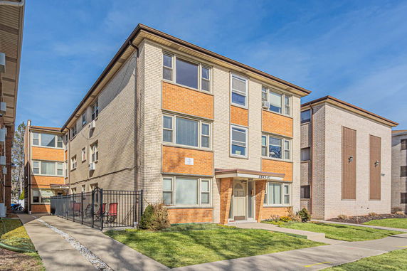 Front view of a multi-story apartment building with a brick facade.