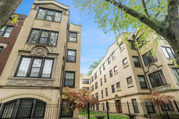 Front view of a brick multi-story apartment building with decorative architectural elements.